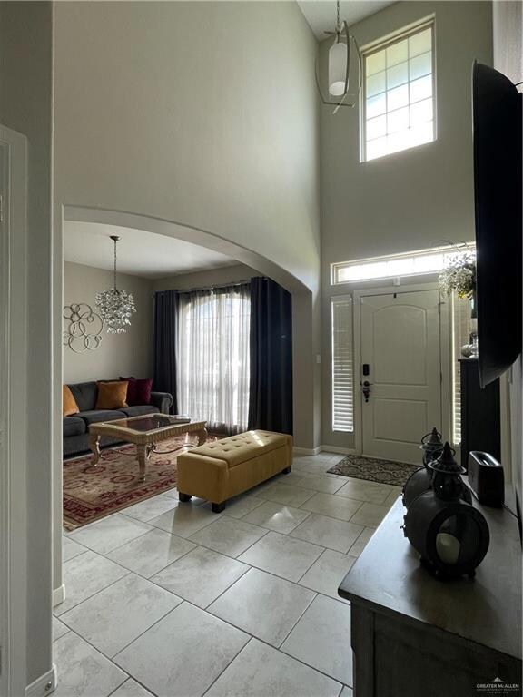 Tiled entrance foyer featuring plenty of natural light, a notable chandelier, and a high ceiling