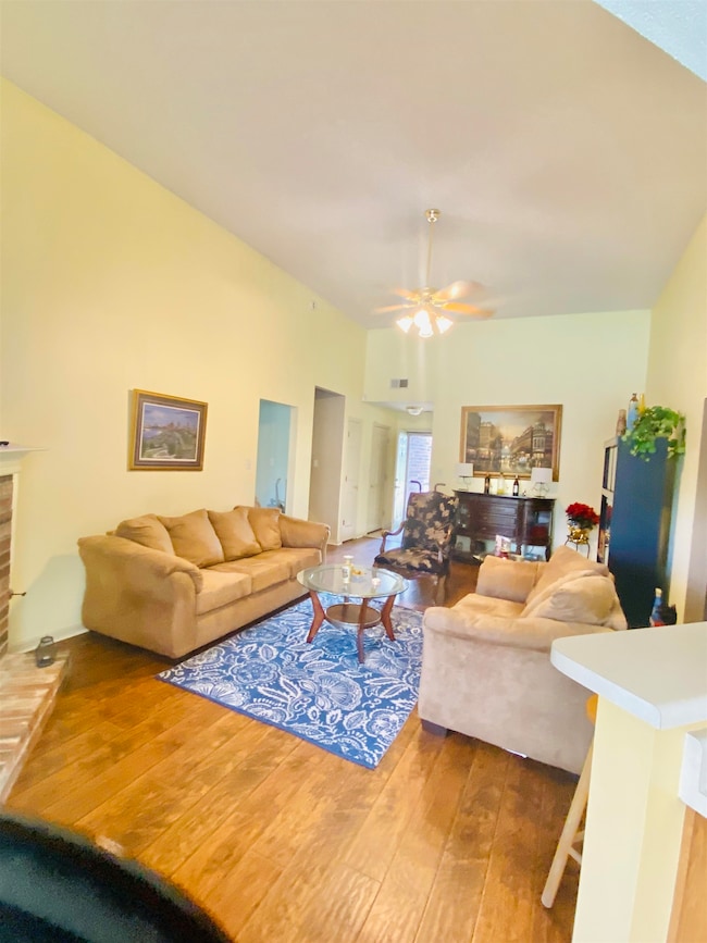 Living area featuring hardwood / wood-style floors, a ceiling fan, and a fireplace with raised hearth
