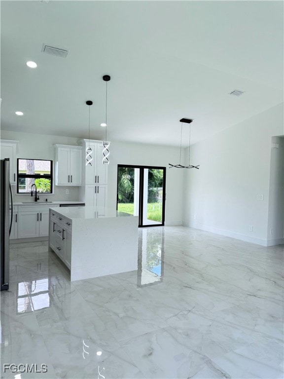 Kitchen with light marble finish floors, pendant lighting, plenty of natural light, and recessed lighting