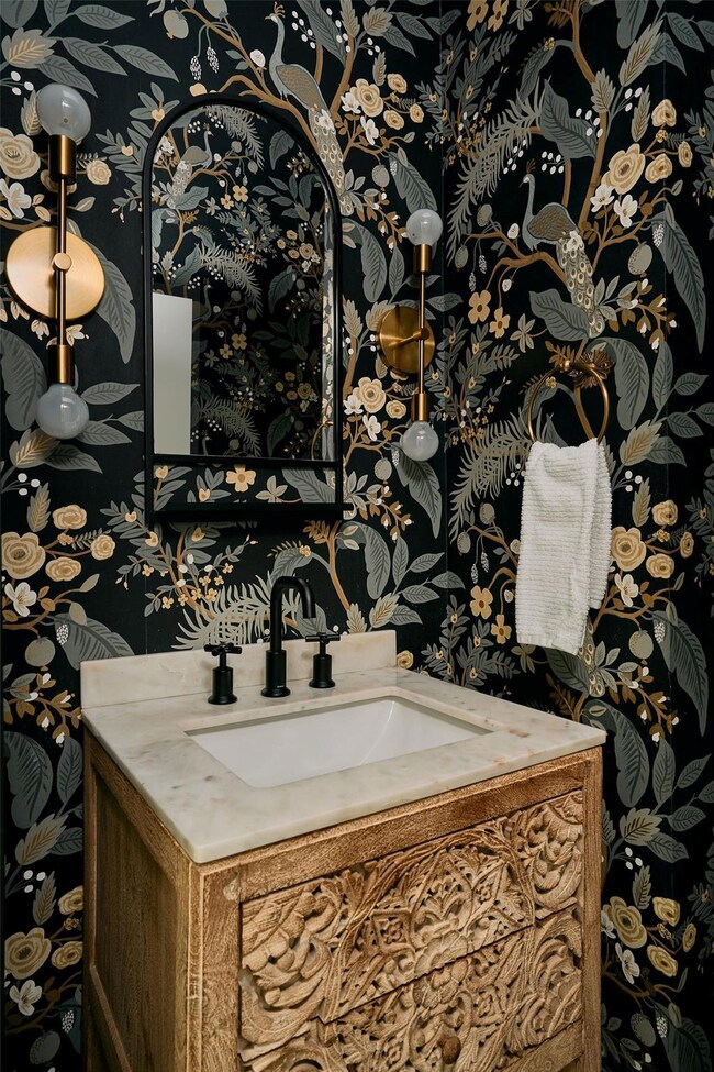 Bathroom with wallpapered walls and vanity
