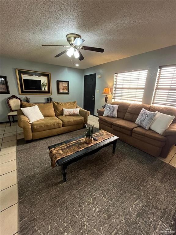Living area featuring a textured ceiling, a ceiling fan, tile patterned flooring, and healthy amount of natural light
