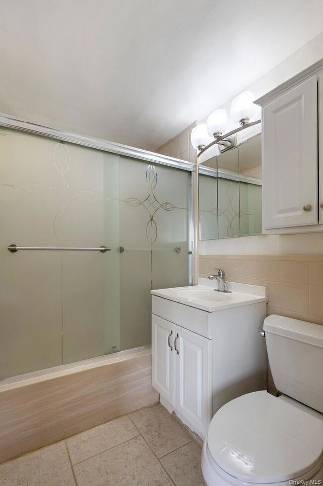 Bathroom with vanity, tile walls, light tile patterned floors, and a stall shower