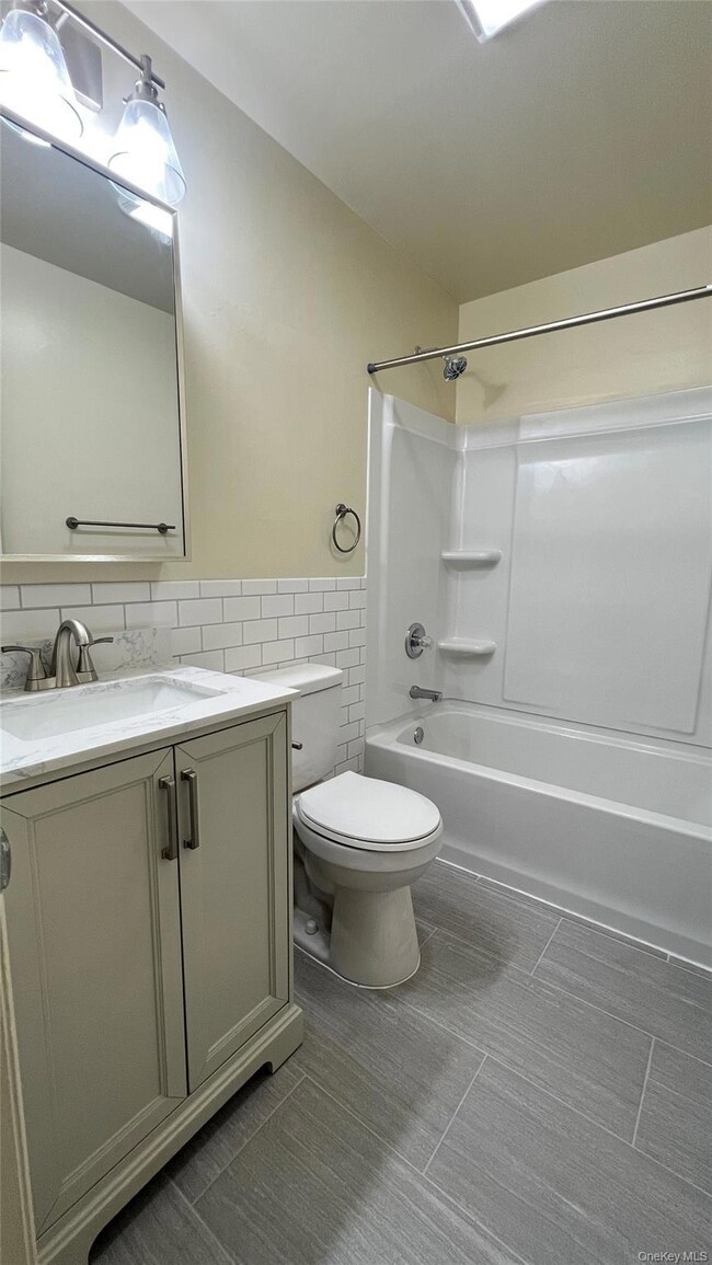 Bathroom with vanity,  shower combination, tile walls, and wainscoting
