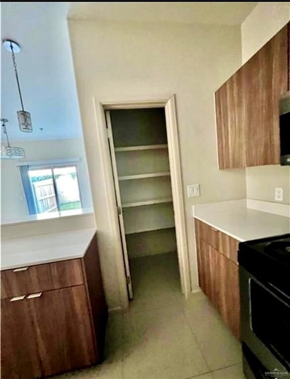 Kitchen with modern cabinets, light tile patterned floors, stainless steel range with electric stovetop, and light countertops