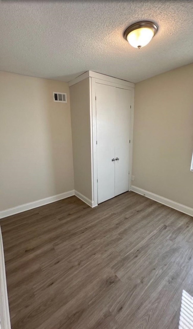 Empty room with a textured ceiling and wood finished floors