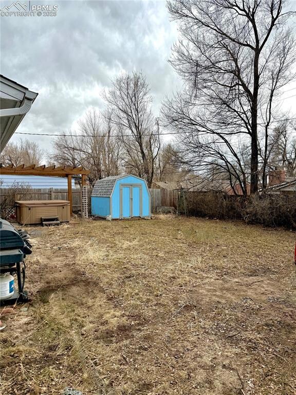View of yard featuring a hot tub and a storage she