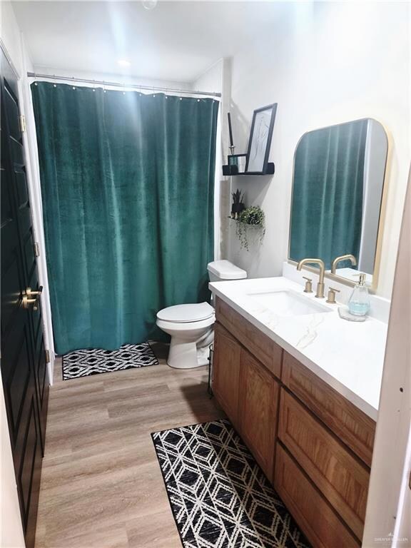Bathroom with vanity, wood finished floors, and a shower with curtain