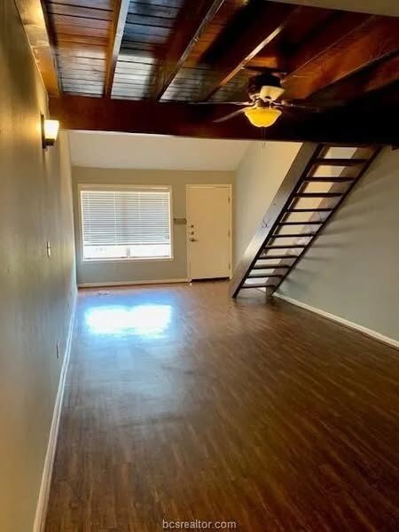 Unfurnished living room with beamed ceiling, hardw