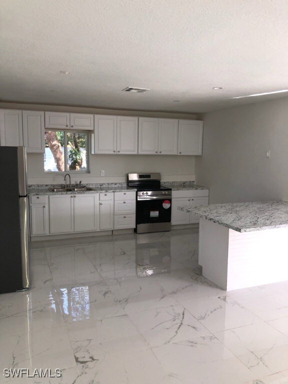 Kitchen with white cabinets, light stone counterto