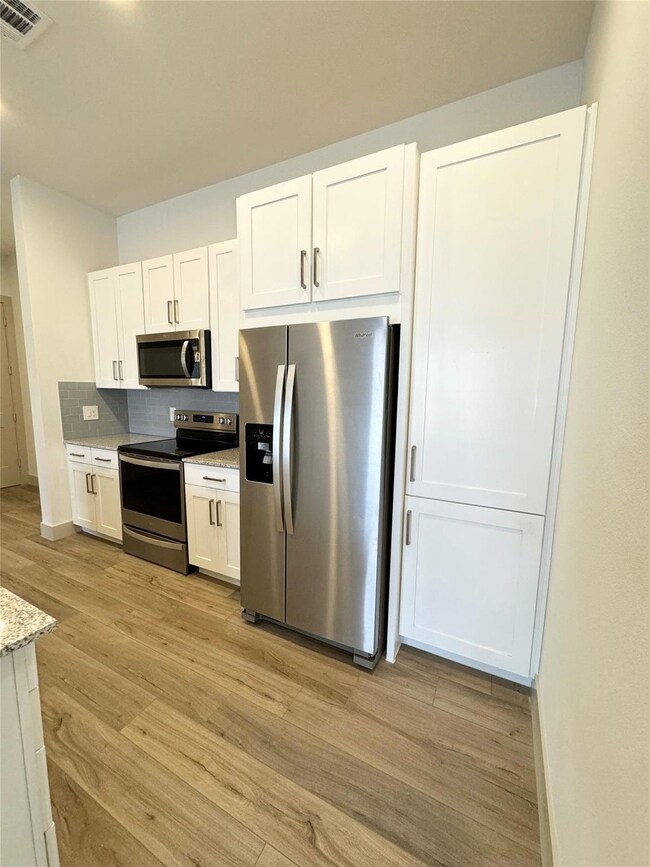 Kitchen with light stone counters, white cabinetry