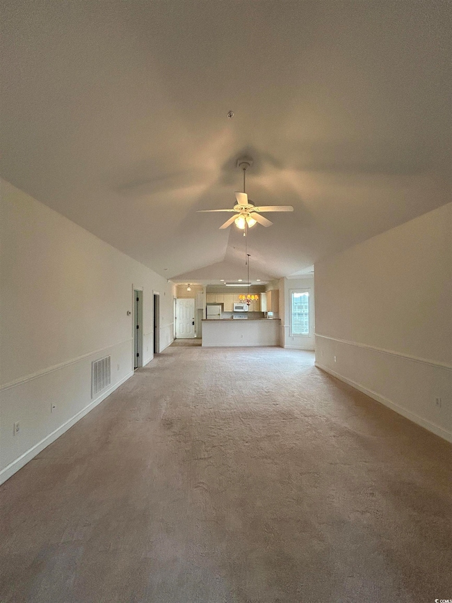 Unfurnished living room featuring ceiling fan with