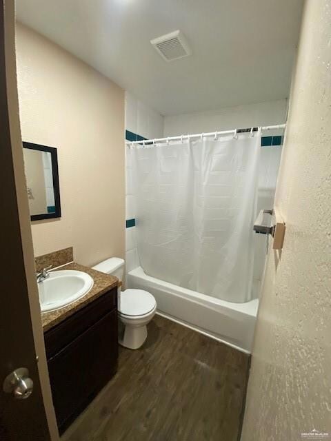 Full bathroom featuring vanity, toilet, shower / tub combo, and hardwood / wood-style floors