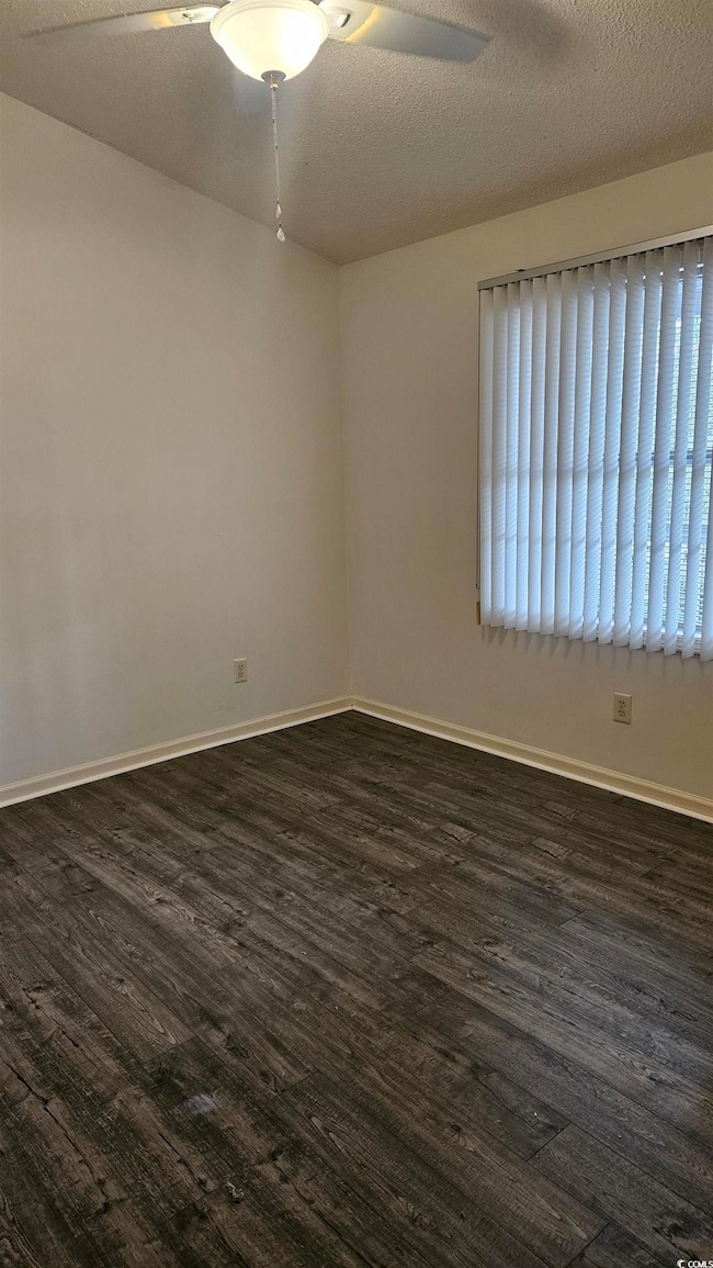 Empty room with a textured ceiling, dark hardwood 