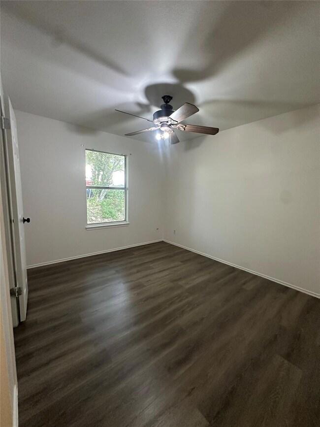 Spare room with ceiling fan and dark wood-style f