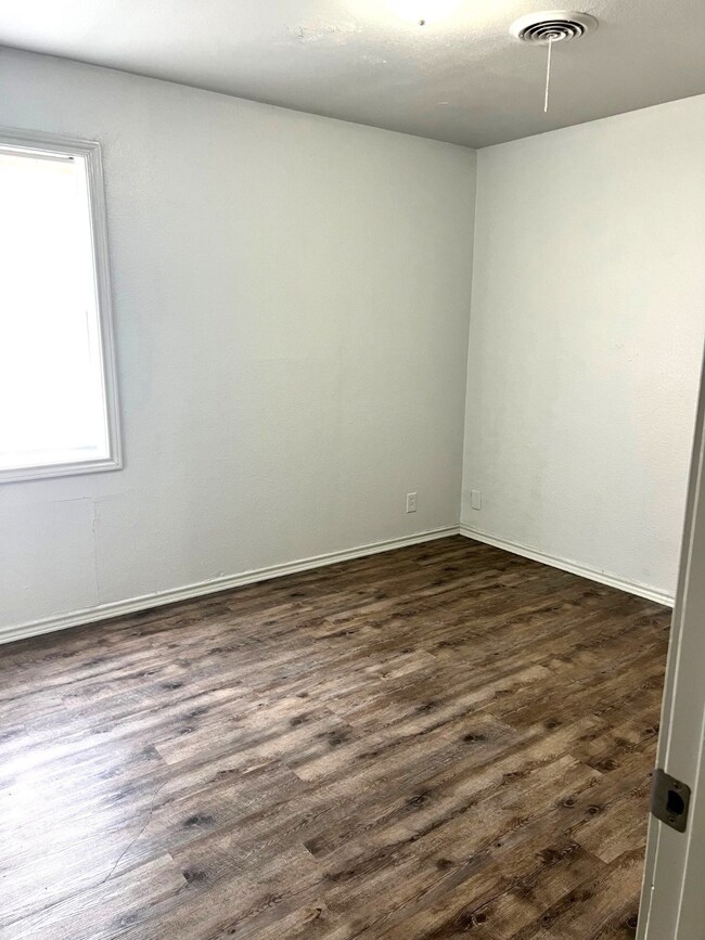Unfurnished room with dark wood-style flooring and baseboards