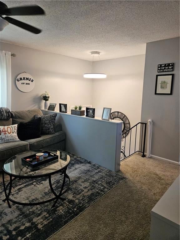 Carpeted living room featuring ceiling fan and a textured ceiling