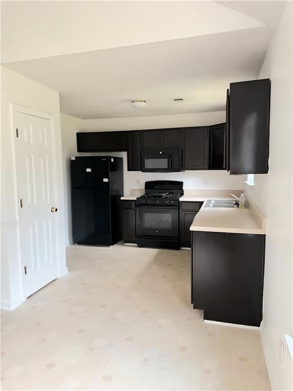 Kitchen featuring appliances, dark cabinetry, and light countertops