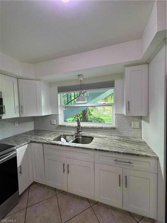 Kitchen featuring range, sink, white cabinetry, de