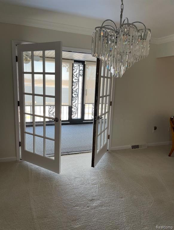 Doorway with ornamental molding, french doors, carpet flooring, and a chandelier