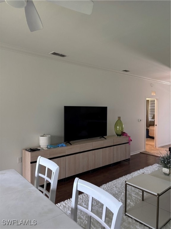 Living room featuring dark wood finished floors, crown molding, and ceiling fan