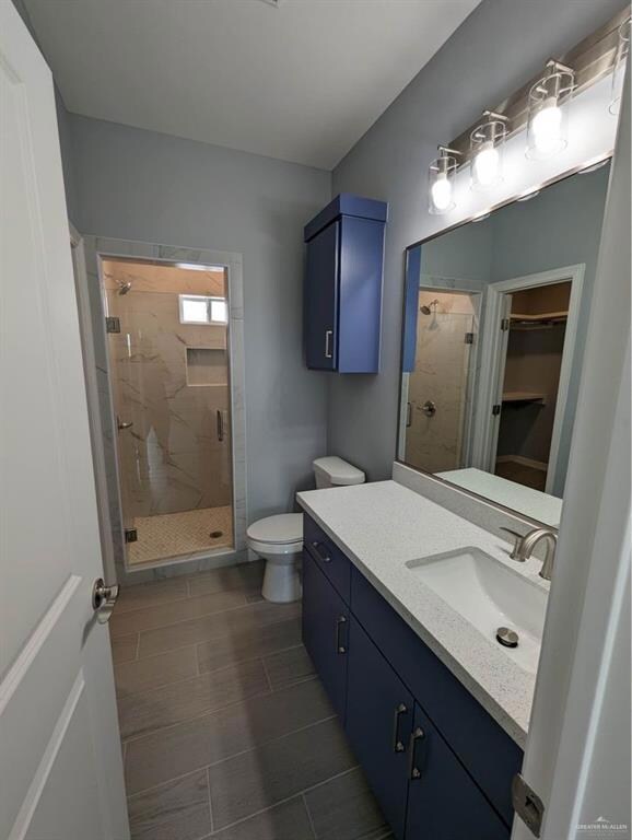 Bathroom featuring vanity, toilet, a tile shower, and tile flooring