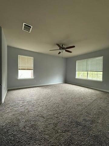 Carpeted empty room featuring visible vents, a ce