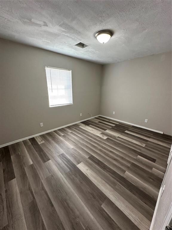 Spare room featuring dark wood-type flooring, a te