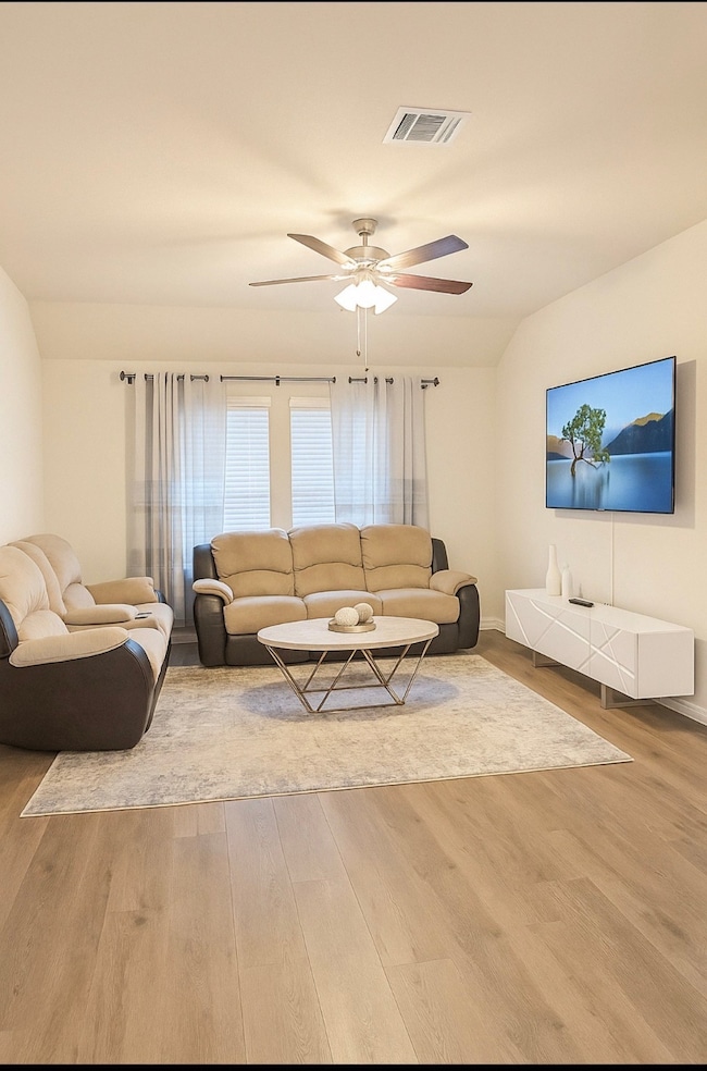 Living room with light wood-style floors, ceiling fan, and vaulted ceiling