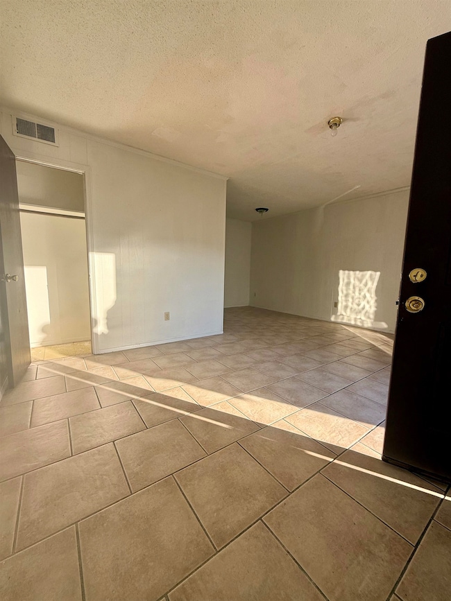 Empty room with a textured ceiling and light tile patterned floors