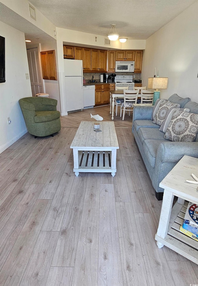 Living area with light wood finished floors and a textured ceiling