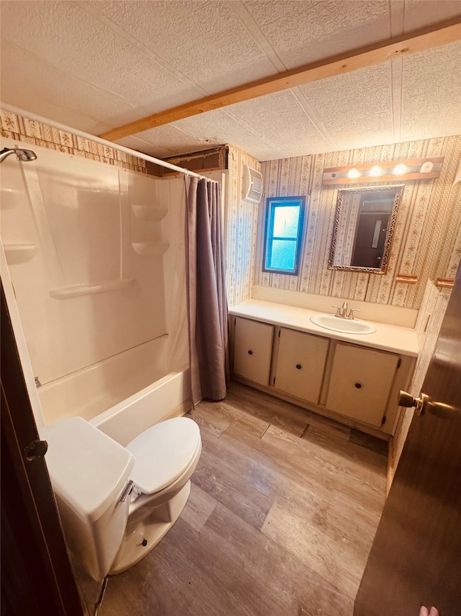 Full bathroom featuring vanity, light wood-type flooring, shower / bath combination with curtain, and wallpapered walls