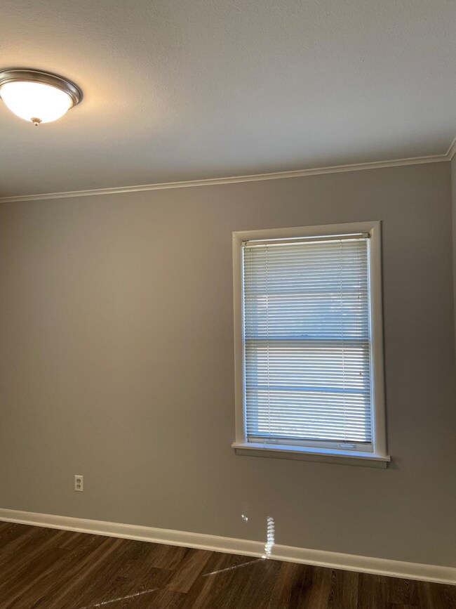 Unfurnished room featuring baseboards, dark wood-style flooring, and crown molding