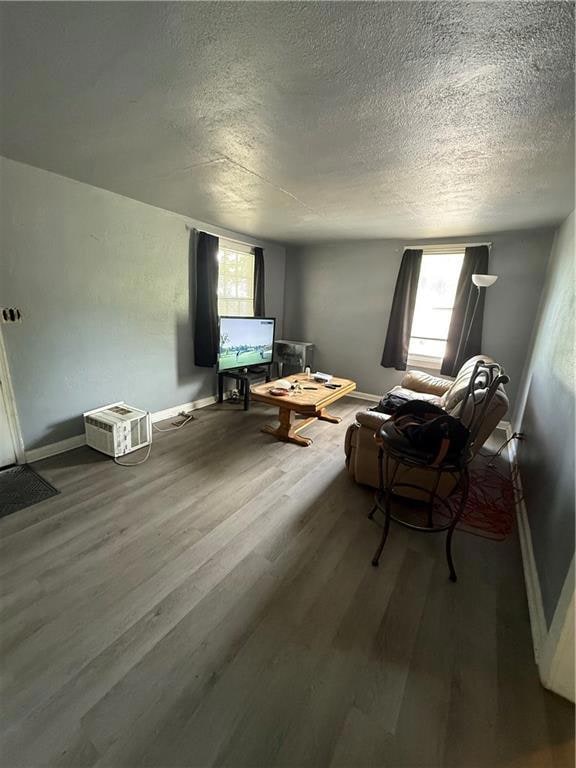 Living room with a textured ceiling, wood finished floors, and baseboards