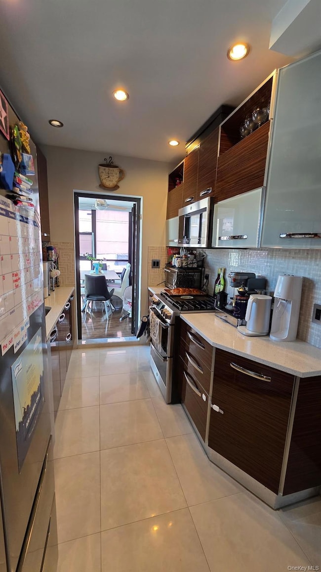 Kitchen with modern cabinets, open shelves, dark brown cabinetry, stainless steel appliances, and tasteful backsplash