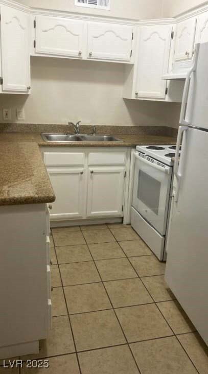 Kitchen with white appliances, light tile patterne