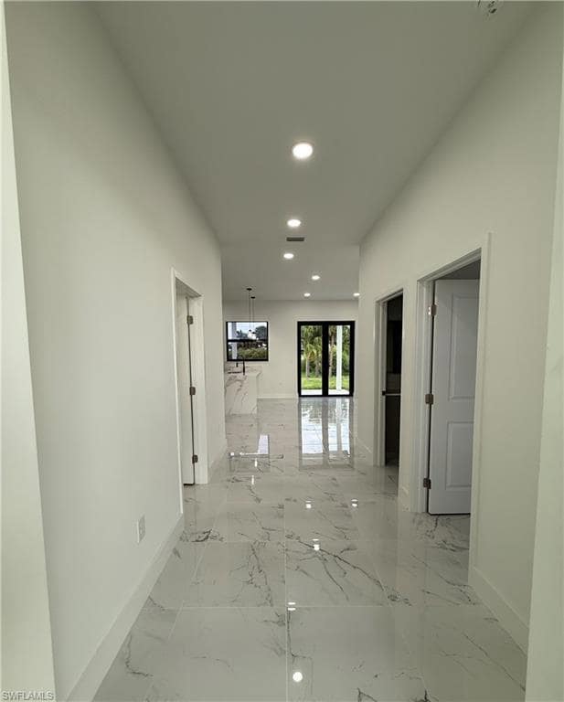 Hallway with light marble finish flooring and recessed lighting