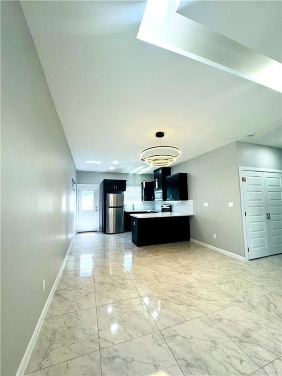 Unfurnished living room with baseboards and light marble finish floors