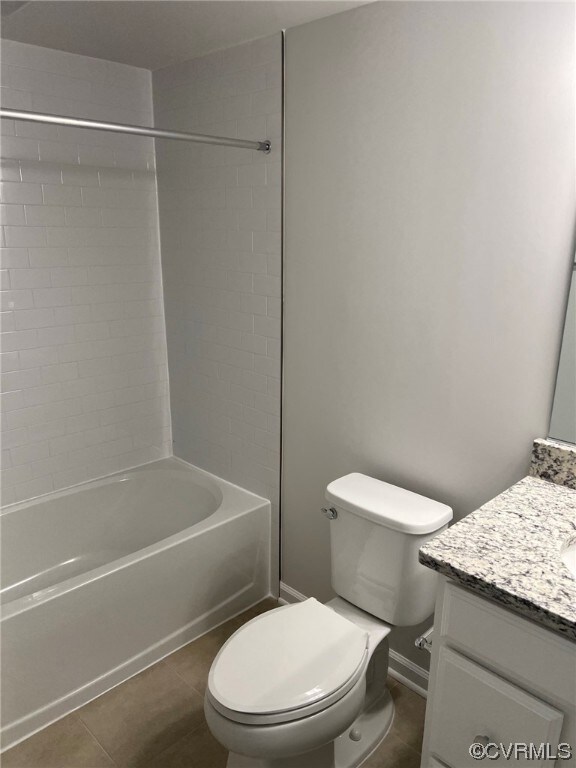 Full bathroom with tiled shower / bath combo, tile floors, vanity, and mirror