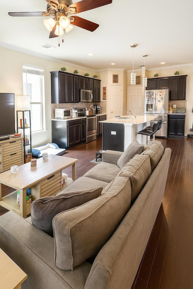 Living room featuring ceiling fan, crown molding,