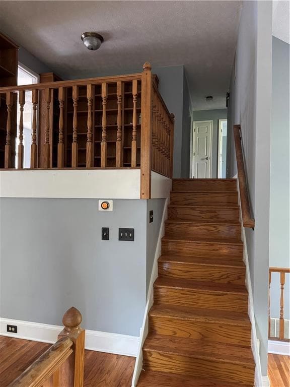 Staircase featuring wood finished floors and a textured ceiling