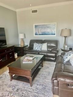 Living room featuring visible vents, ceiling fan, crown molding, and wood finished floors