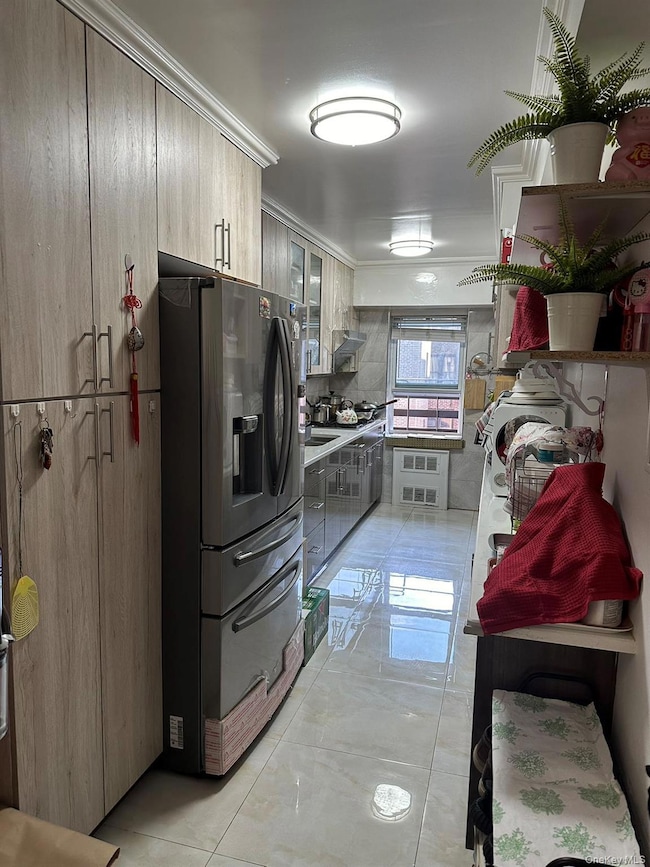Kitchen featuring glass insert cabinets, stainless steel refrigerator with ice dispenser, light countertops, and crown molding