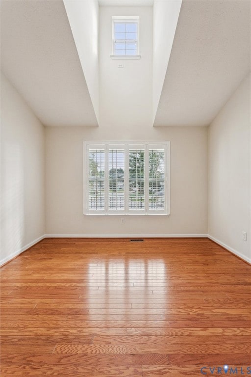 Unfurnished living room with light wood-style floors and a towering ceiling