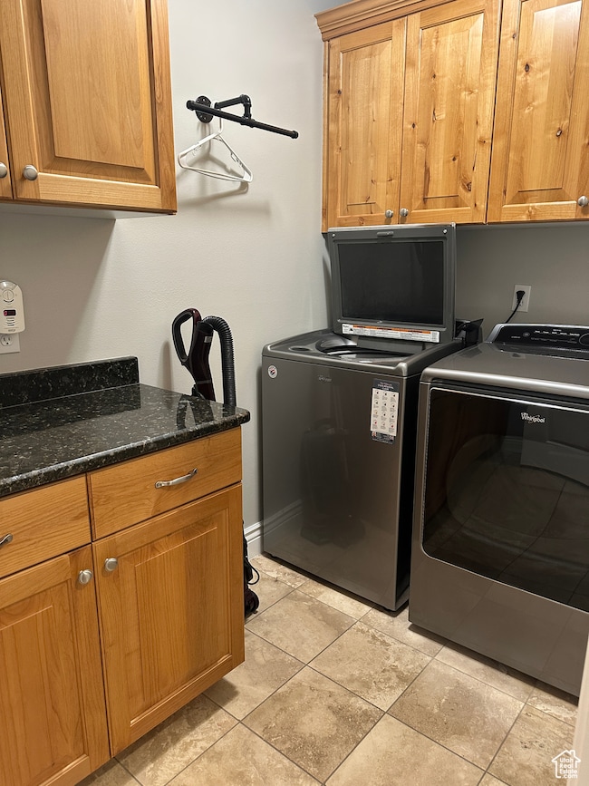 Laundry area featuring cabinet space, washer and clothes dryer, and light tile patterned flooring