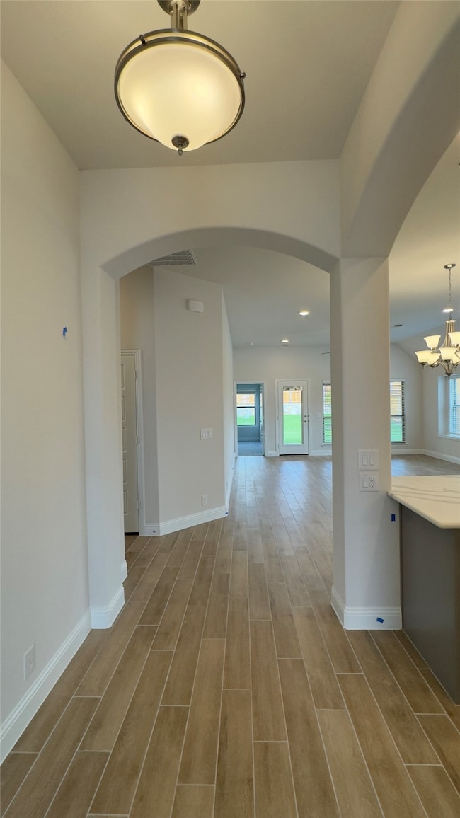 Hallway featuring arched walkways, wood finished floors, and plenty of natural light