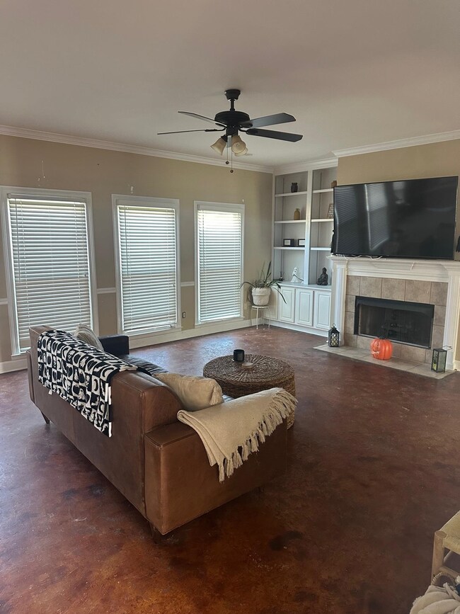 Living room featuring crown molding, a fireplace, and ceiling fan