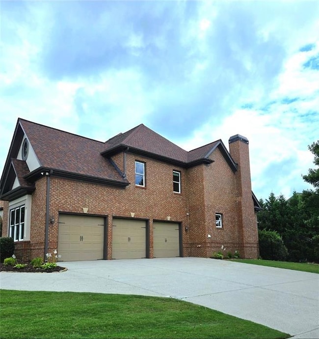 View of property exterior with concrete driveway, brick siding, a chimney, a yard, and a garage