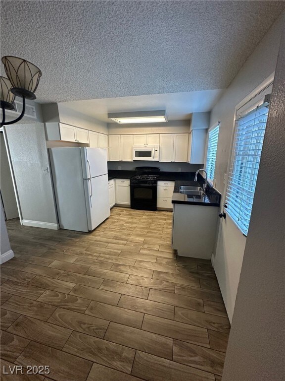Kitchen with white appliances, dark countertops, a