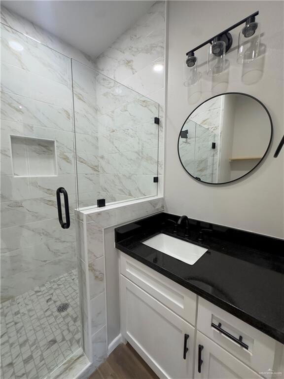 Full bathroom featuring vanity, a stall shower, and wood finished floors