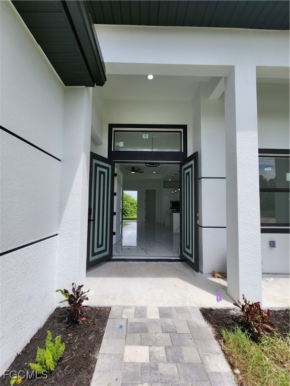 View of exterior entry featuring stucco siding and a patio area